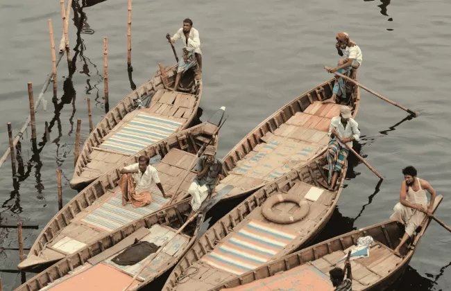 Group of fishermen in wooden boats using traditional fishing nets on a river.