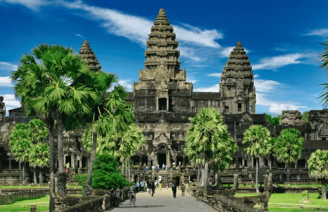 Angkor Wat temple complex surrounded by greenery under a bright blue sky in Cambodia.