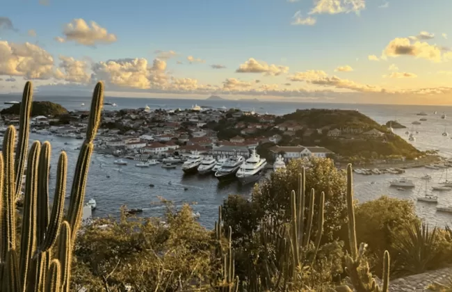 Sun setting over a harbor with boats and an island.