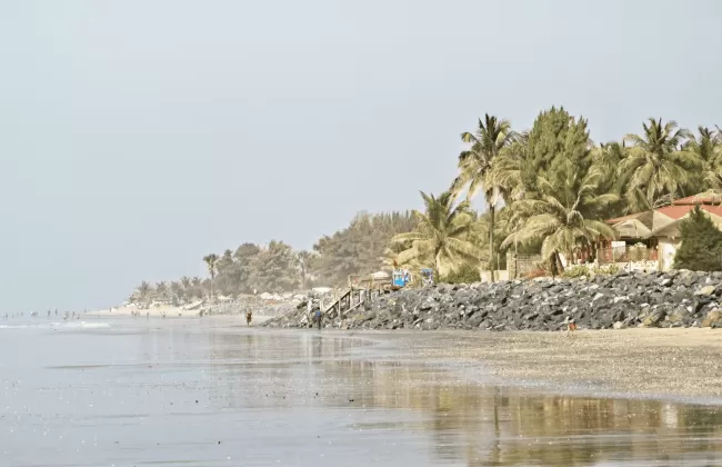 A coastline with calm shallow water and houses on the shore.