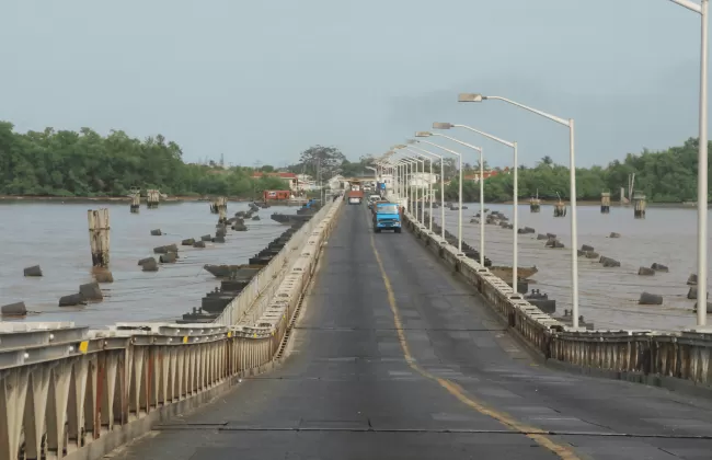 A long bridge over water with streetlights and vehicles.