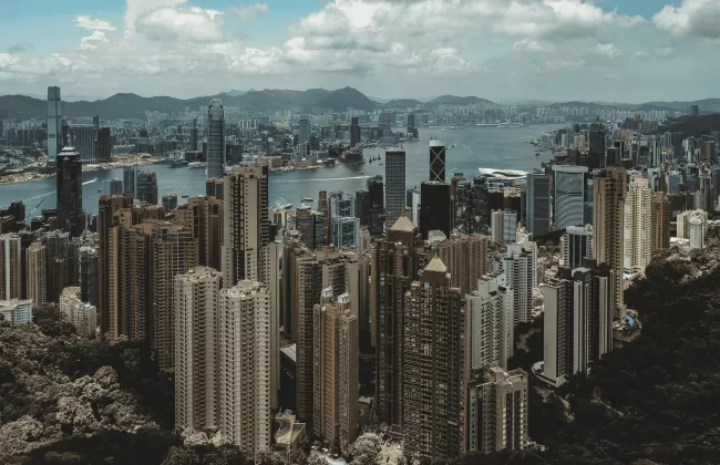 A dense skyline of tall buildings in Hong Kong, viewed from above.