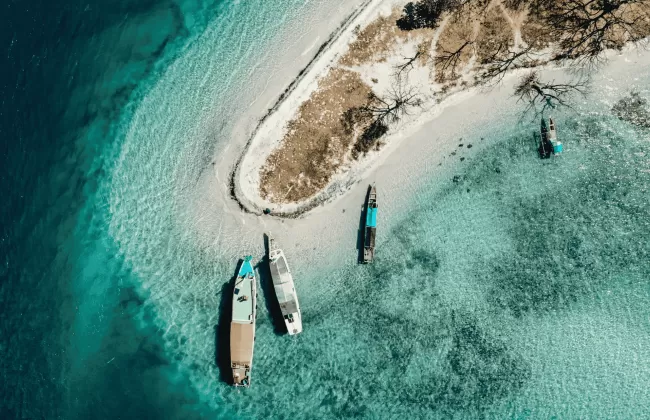 An aerial view of small tropical island with sandy beach and turquoise waters.