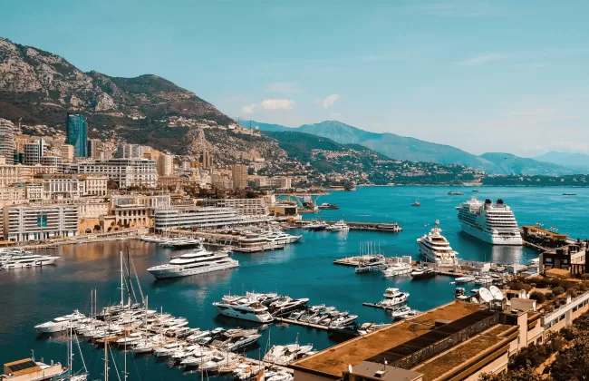 Harbor with yachts and buildings on a hillside.