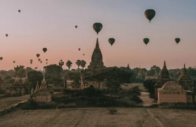Hot air balloons flying over a plain with temples.