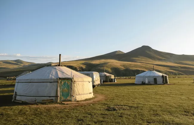 Traditional yurts on grassy plains.