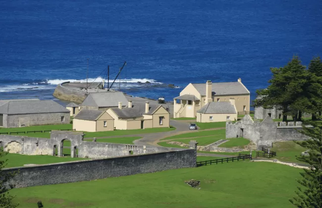 A small coastal village with green fields and the ocean beyond.