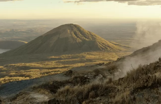 A smoking volcano with ash rising into the sky.