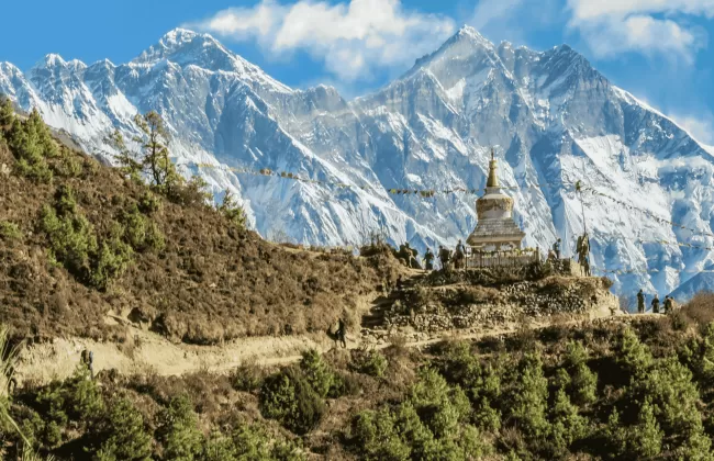 A snow-capped mountains towering above green hills in the foreground.