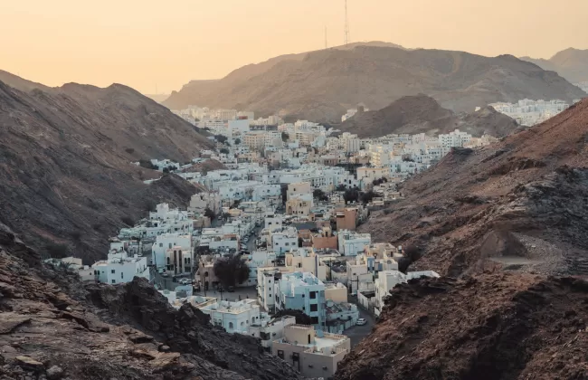 A white village nestled between steep, rocky desert mountains.