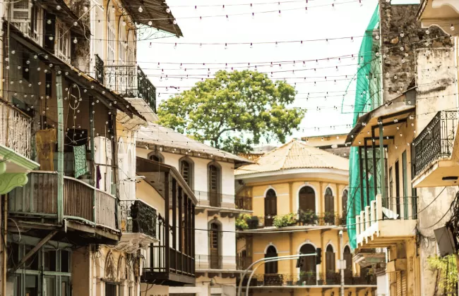 A narrow street with colonial-style buildings and balconies with plants.