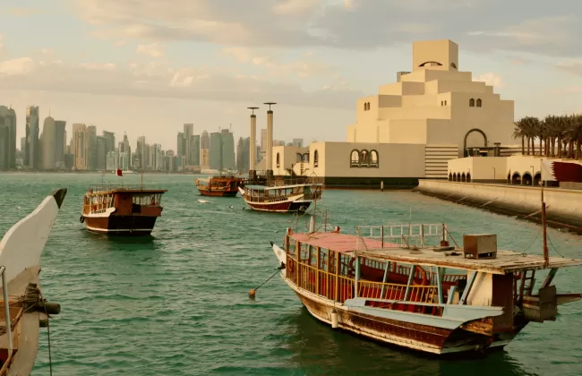Boats docked in a harbor with a modern city skyline in the background.