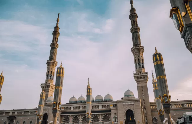 A grand mosque with multiple tall minarets under a blue sky.