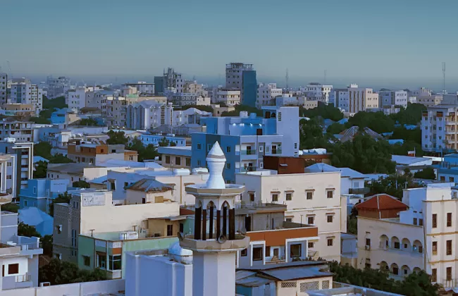 A cityscape with white and blue buildings under a clear sky.