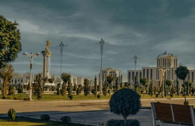 Ornate mosque and gardens with domes and minarets under a cloudy sky.