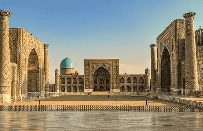 Ornate Islamic architecture with domes and tall minarets reflecting in a courtyard pool.