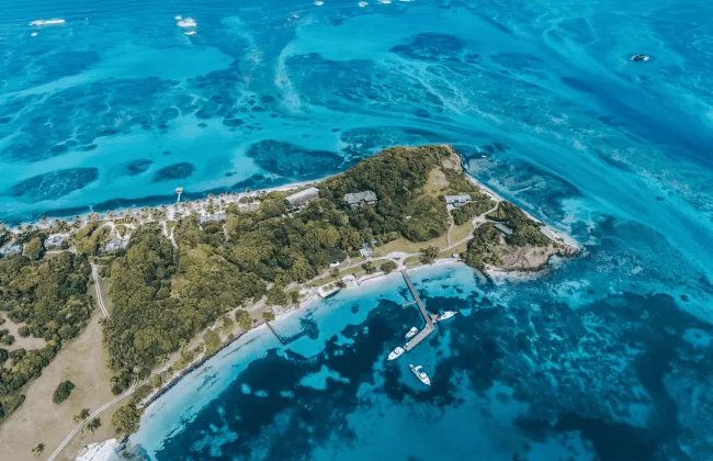 Aerial view of a small tropical island surrounded by bright blue waters.