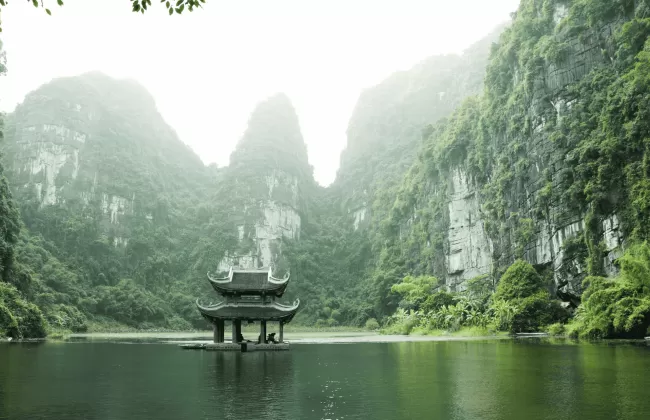 Pagoda surrounded by body of water and mountains.