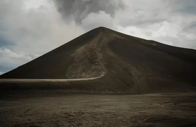 Dark volcanic cone with smoke rising from the crater.