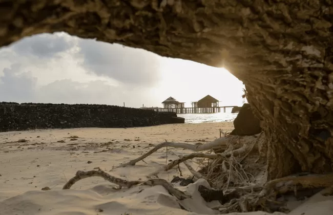 A sandy beach framed by a rocky cave opening.