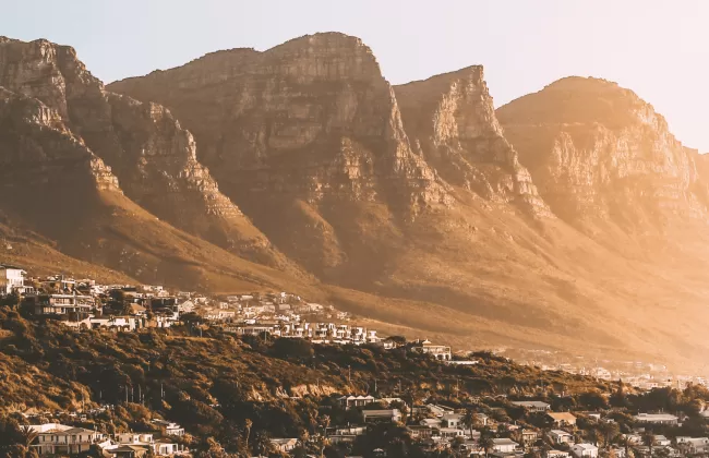 Rugged golden mountains with a city nestled at their base.