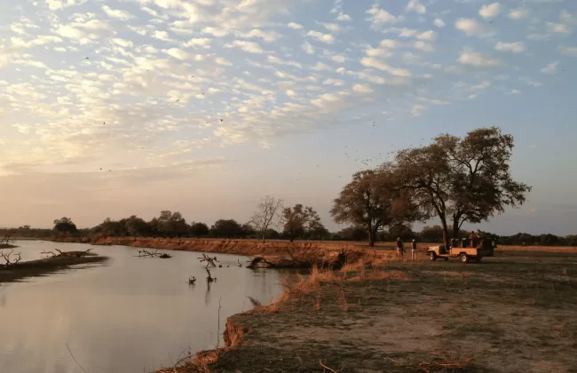 A large body of water sitting next to a lush green field.
