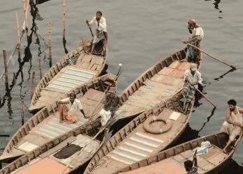 Group of fishermen in wooden boats using traditional fishing nets on a river.