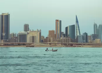 Modern skyline of Manama, Bahrain, with high-rise buildings viewed across the water.