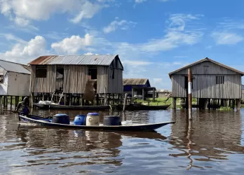 Traditional stilt houses and a boat on a calm waterway in a lakeside village in Benin.