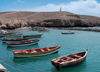 Traditional fishing boats moored in a calm bay with arid hills in the background in Cape Verde.