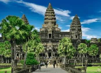 Angkor Wat temple complex surrounded by greenery under a bright blue sky in Cambodia.