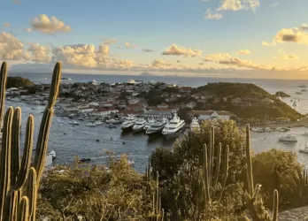 Sun setting over a harbor with boats and an island.