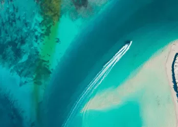 Aerial view of a tropical shoreline with turquoise waters and a speedboat.