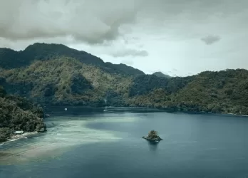 A calm lake surrounded by forested mountains.