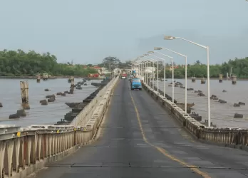 A long bridge over water with streetlights and vehicles.