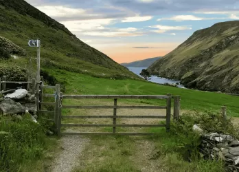 A peaceful countryside path through rolling green hills on the Isle of Man.