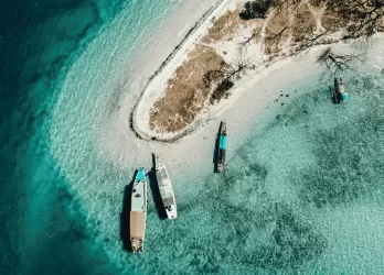 An aerial view of small tropical island with sandy beach and turquoise waters.
