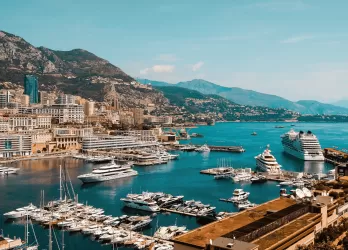 Harbor with yachts and buildings on a hillside.