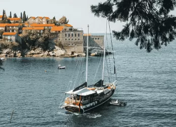 Coastline with cliffs, greenery, and a sailing boat.