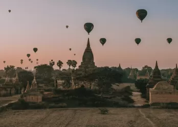 Hot air balloons flying over a plain with temples.