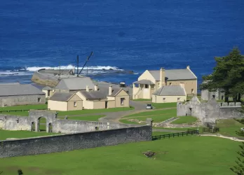 A small coastal village with green fields and the ocean beyond.
