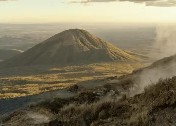 A smoking volcano with ash rising into the sky.