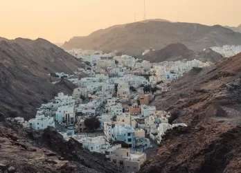A white village nestled between steep, rocky desert mountains.