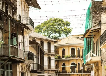 A narrow street with colonial-style buildings and balconies with plants.