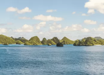 A group of small green islands surrounded by bright blue tropical water.