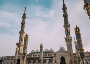 A grand mosque with multiple tall minarets under a blue sky.