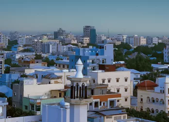 A cityscape with white and blue buildings under a clear sky.