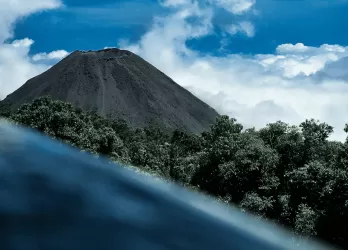 A volcanic crater with a blue lake seen from above.