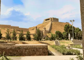 Ancient fortress ruins with stone walls under a blue sky.