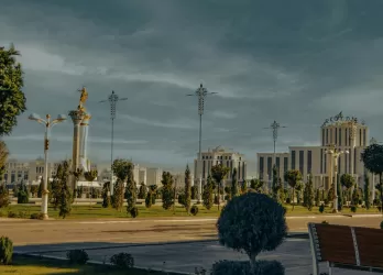 Ornate mosque and gardens with domes and minarets under a cloudy sky.